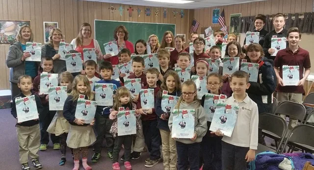 A class of students and teachers holding copies of Tommy Tablet at Niagara Falls.
